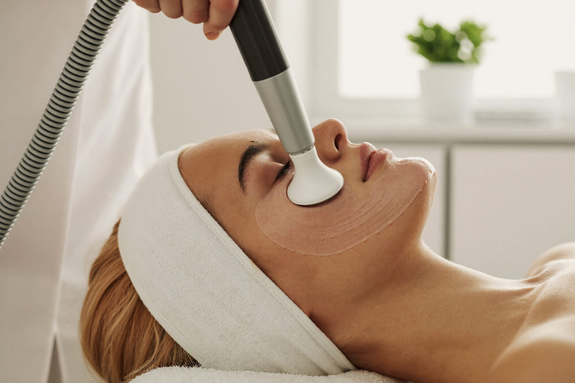 HydraFacial vortex handpiece gliding across a client’s cheek